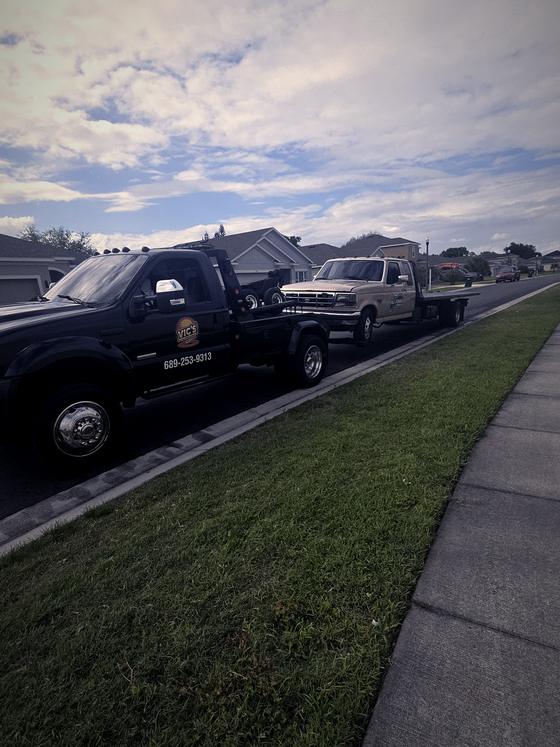A pickup secured on a flatbed with Vic's wrecker alongside.