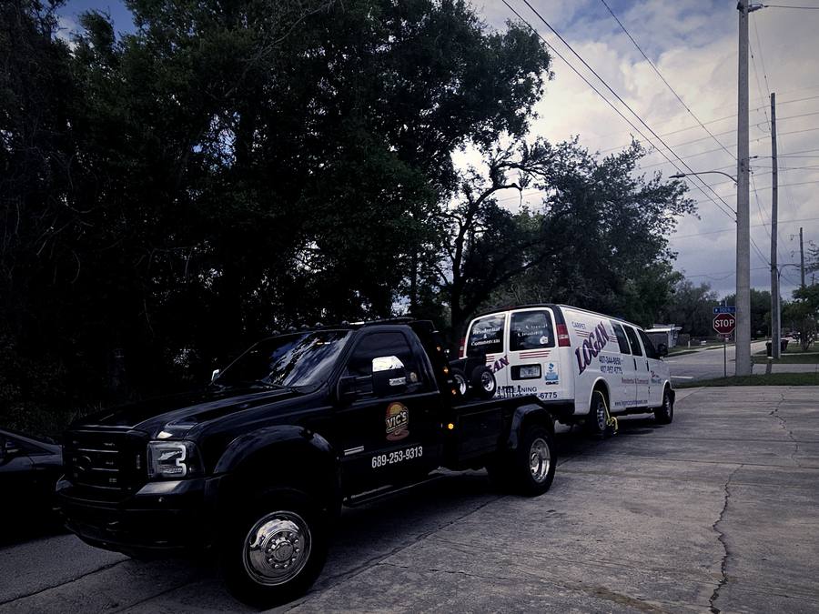 A white work van loaded for junk vehicle removal.